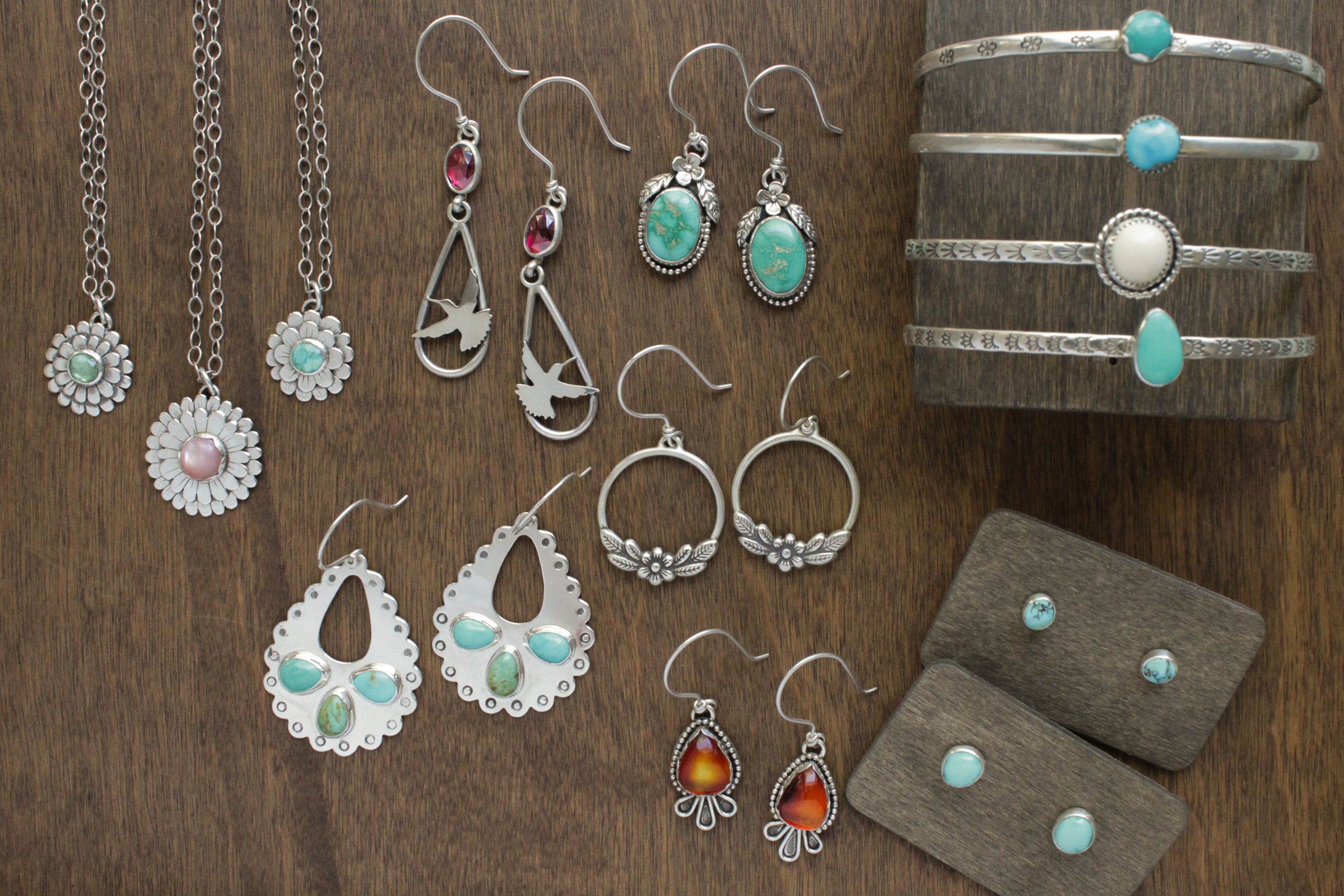 Collection of silver jewelry with gemstones on a wooden surface