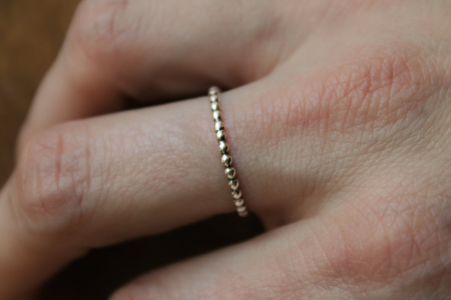 Sterling Silver beaded stacker ring on a finger with a blurred background