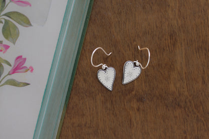 Handmade Valentine’s Day earrings with whimsical silver heart designs, responsibly crafted from recycled sterling silver.