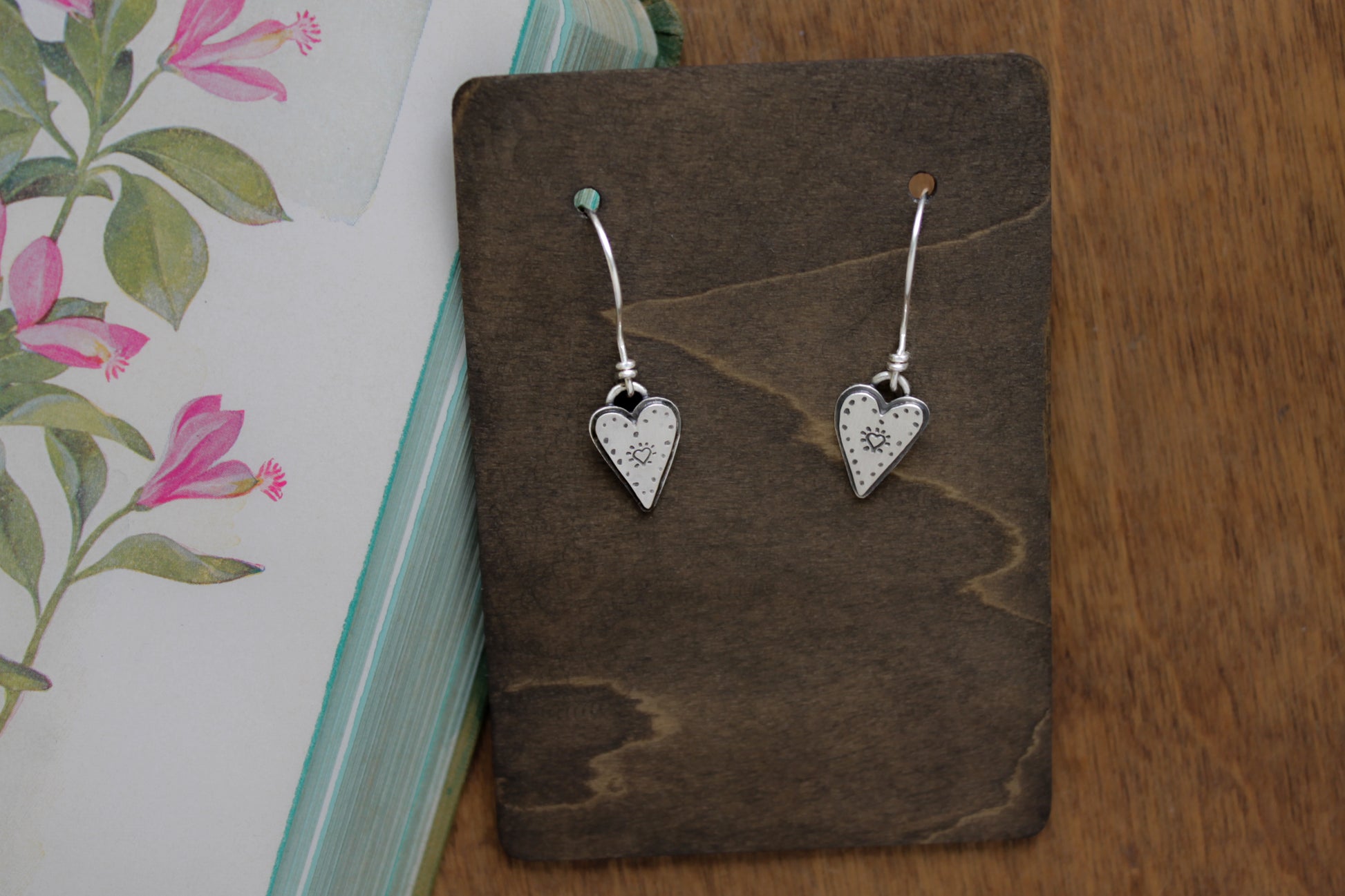 Small sterling silver dangle earrings with hand-stamped heart designs inspired by playful love doodles, perfect for Valentine’s Day gifts.