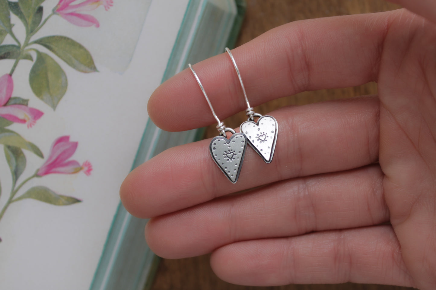 Handcrafted sterling silver earrings featuring dainty heart motifs, responsibly made from recycled materials with a nostalgic romantic touch.