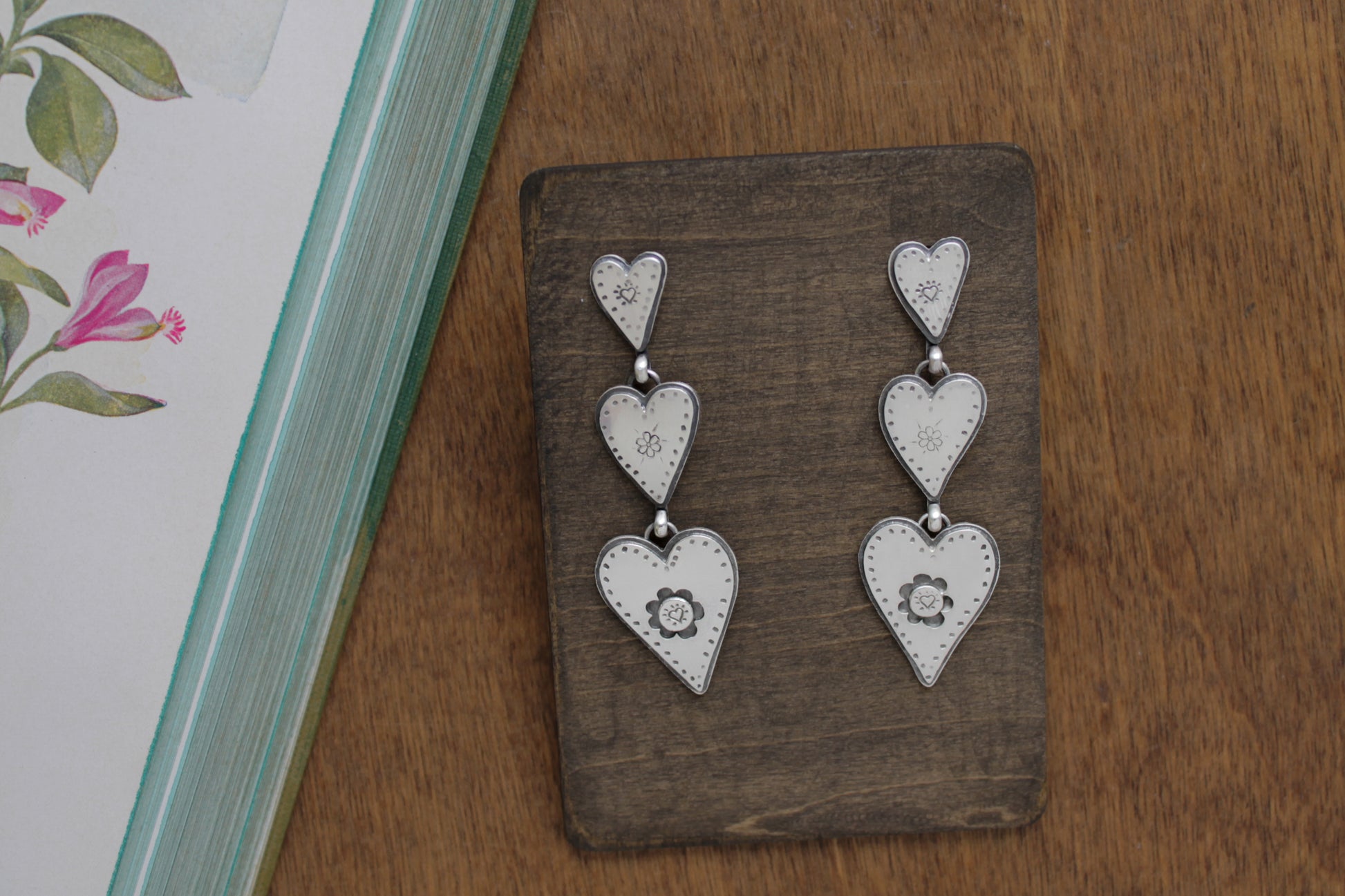 Romantic silver heart earrings with whimsical designs, connected by graceful jump rings for a charming Valentine’s Day accessory