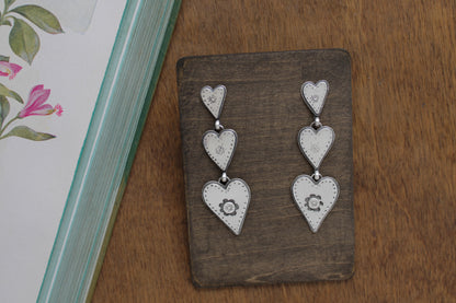 Romantic silver heart earrings with whimsical designs, connected by graceful jump rings for a charming Valentine’s Day accessory