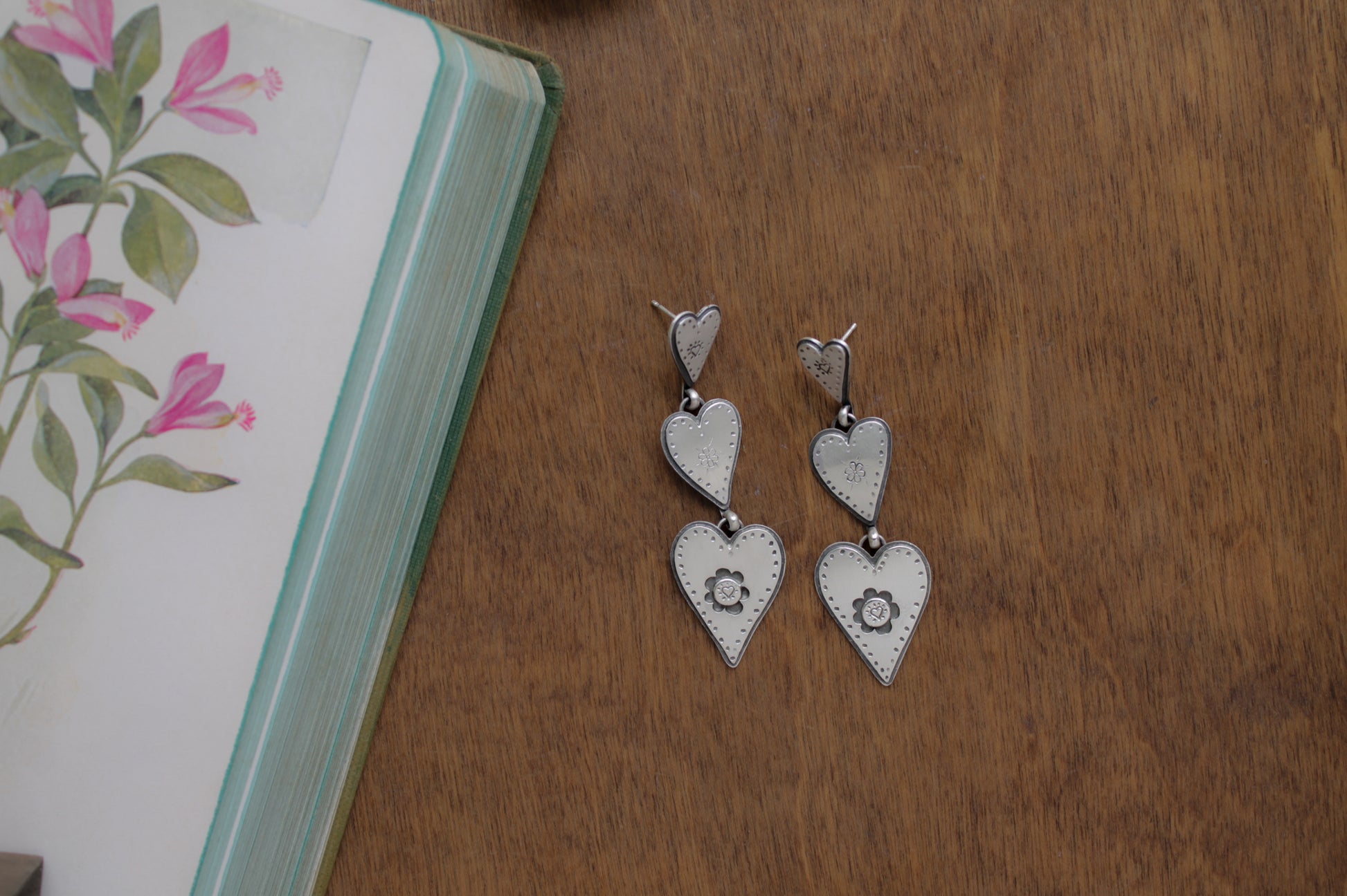 Whimsical sterling silver earrings with three connected hearts, evoking the sweet nostalgia of daydreaming about first love.