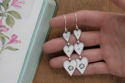 Whimsical heart earrings with playful hand-stamped designs, crafted from recycled sterling silver for a timeless Valentine’s Day statement.