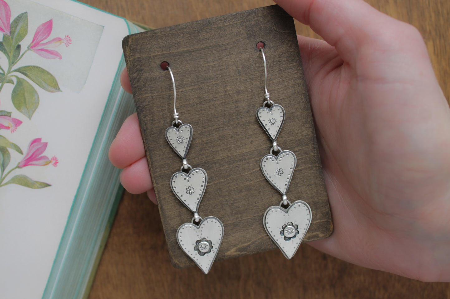 Romantic dangle earrings with three sterling silver hearts, hand-stamped with love-inspired details and crafted for sustainable style.