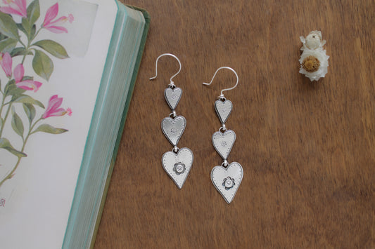 Drawn to You statement earrings featuring three sterling silver hearts with whimsical hand-stamped details, perfect for Valentine’s Day or a romantic gift.