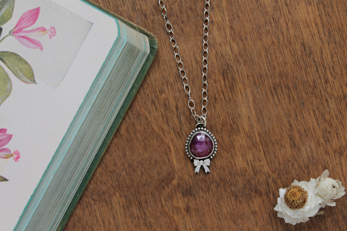 Delicate silver ruby necklace featuring a hand-sawn bow and adjustable sterling silver chain, ideal for timeless feminine style.