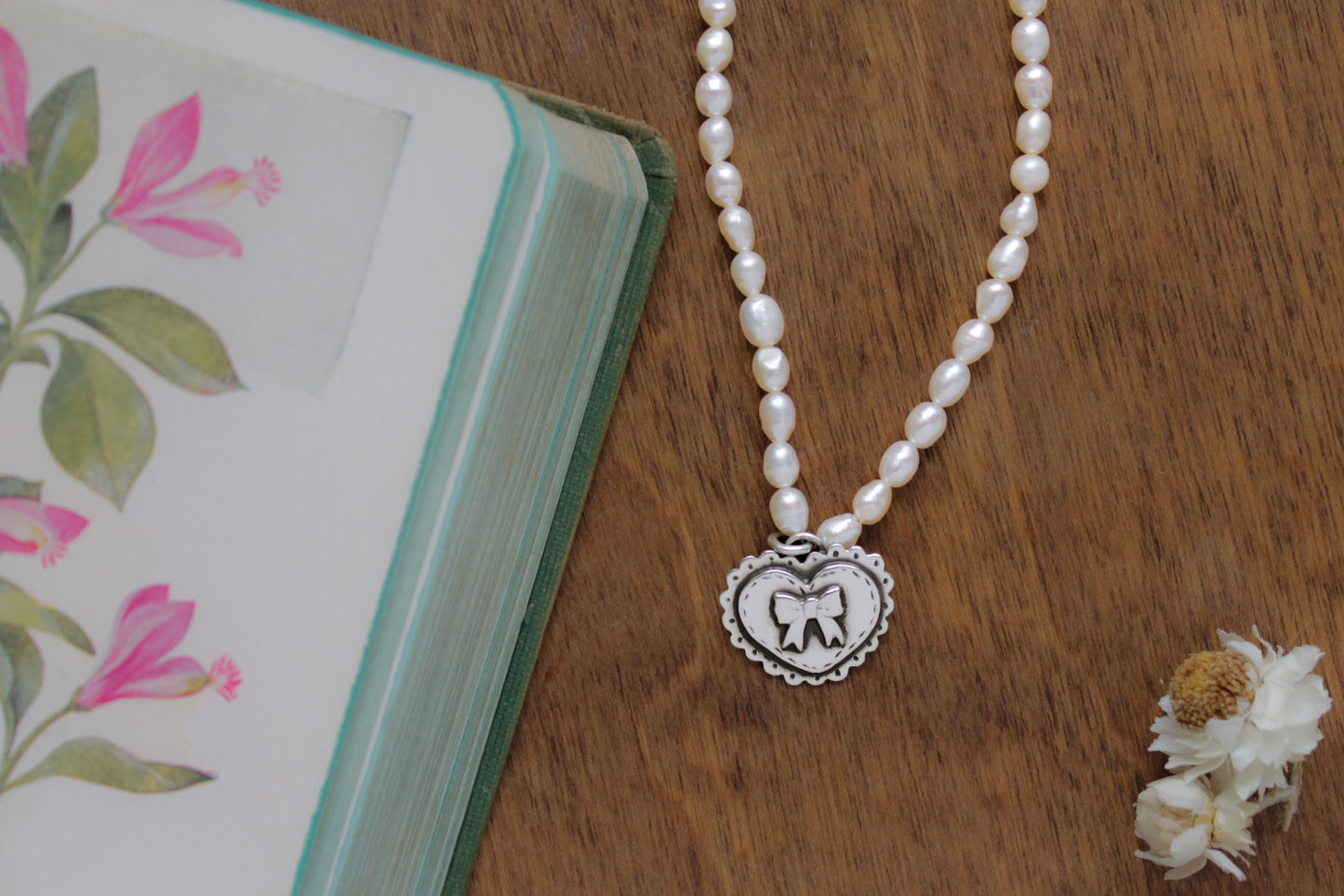 Love Bound Necklace featuring a hand-stamped silver heart pendant on a pearl strand, perfect for romantic and heartfelt gifts