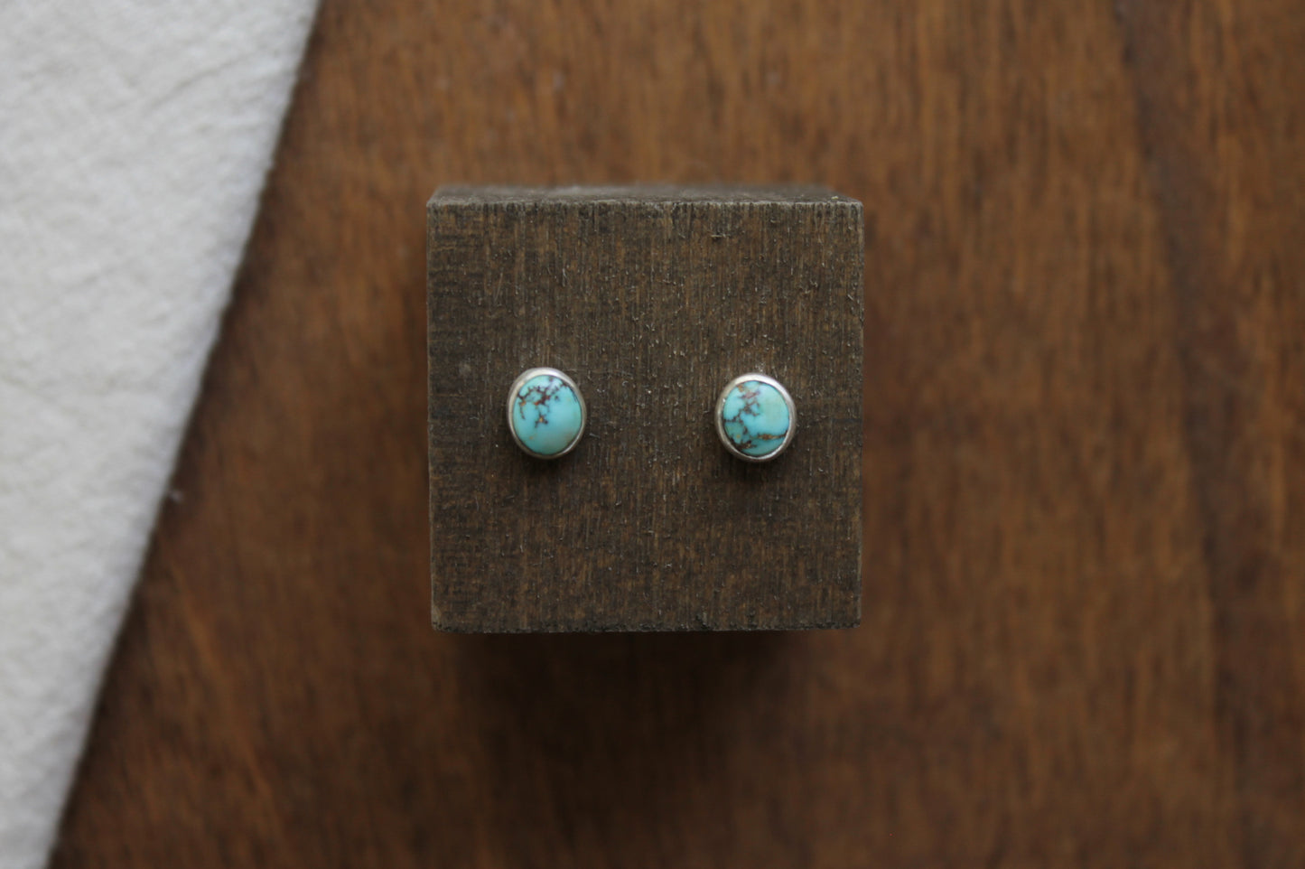 Turquoise stud earrings on a wooden display block