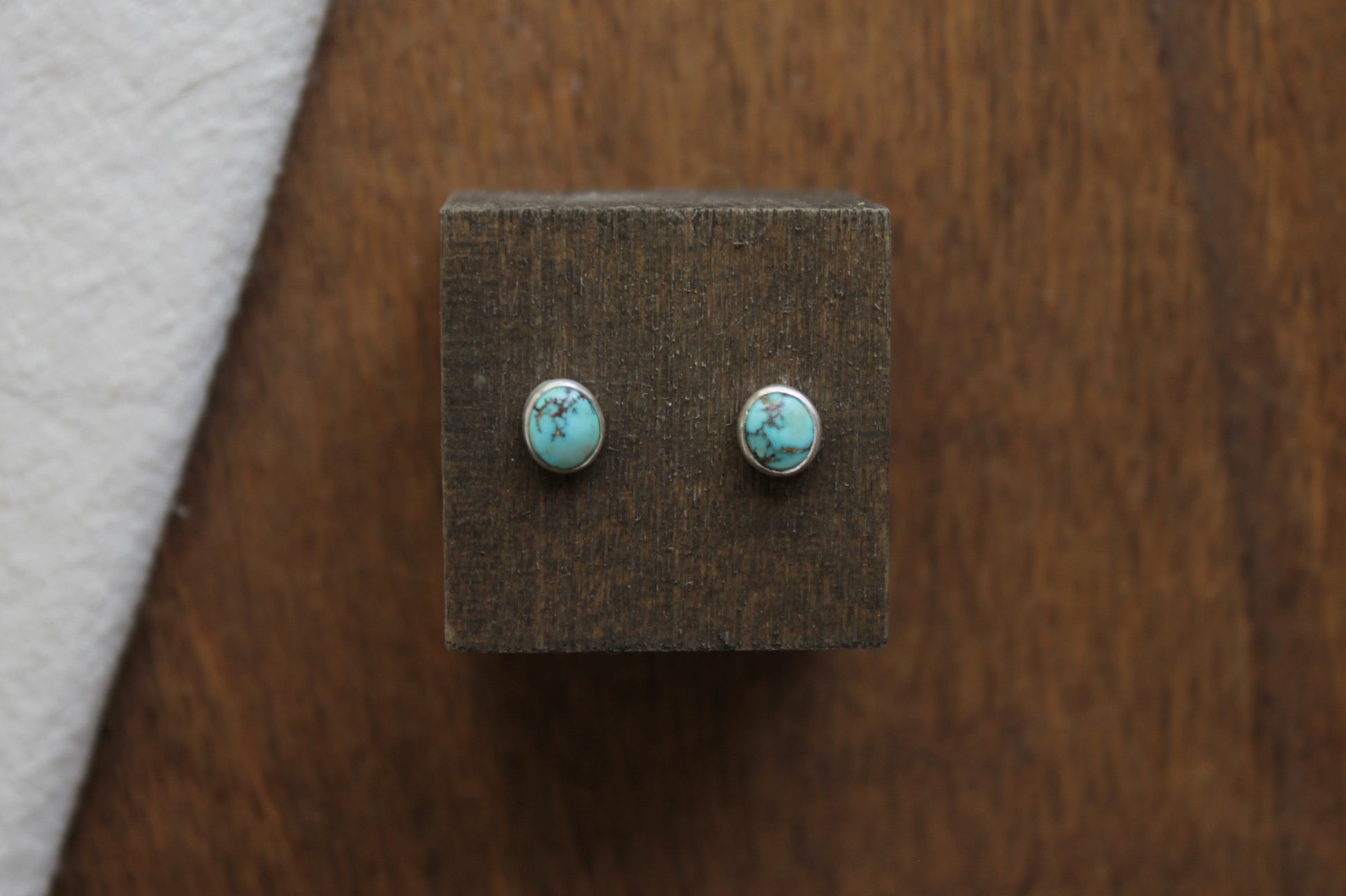 Turquoise stud earrings on a wooden display block
