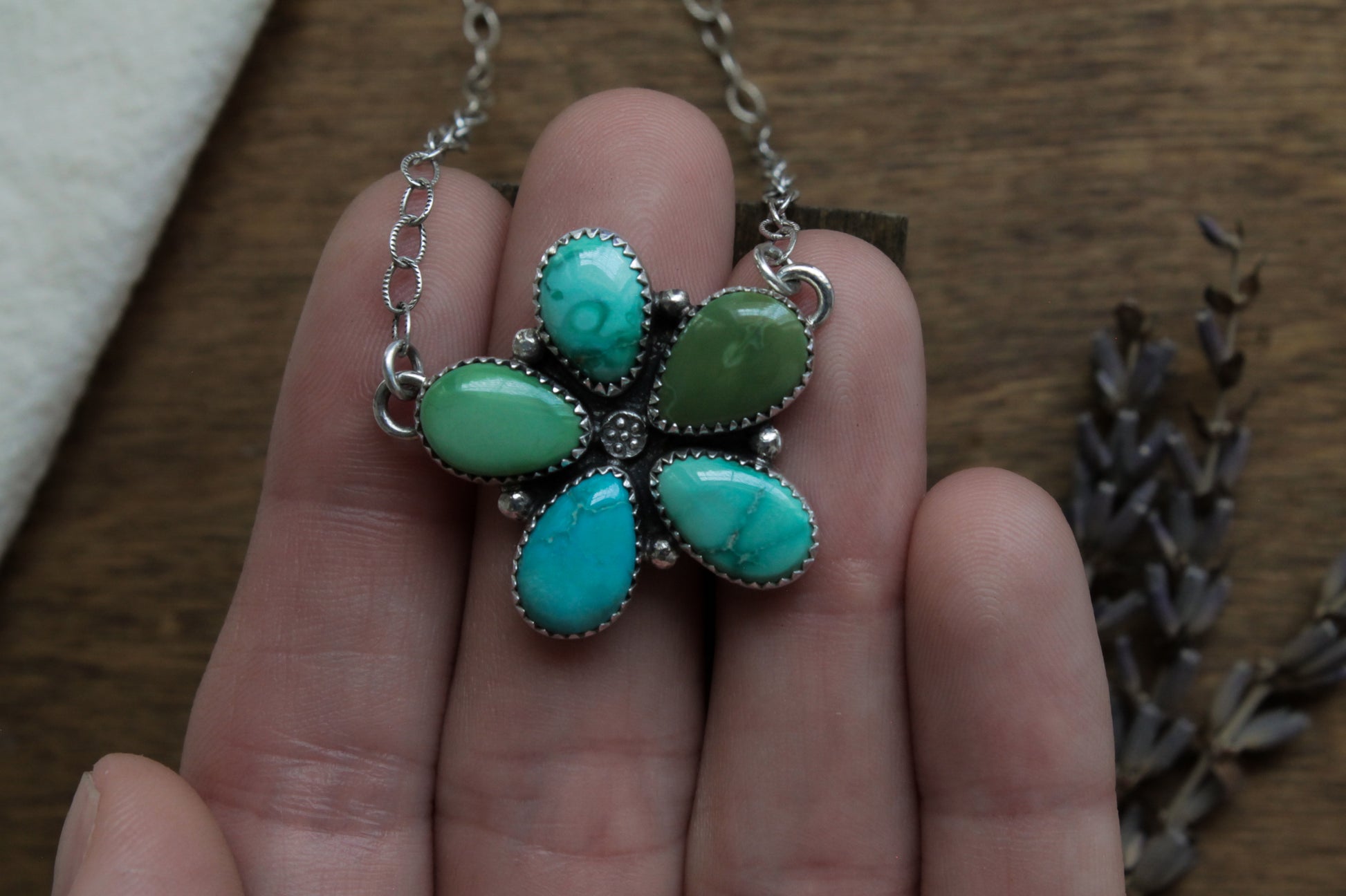 Statement turquoise necklace with genuine Emerald Valley Turquoise stones, hand-formed into a wildflower pendant design with sustainable recycled sterling silver.