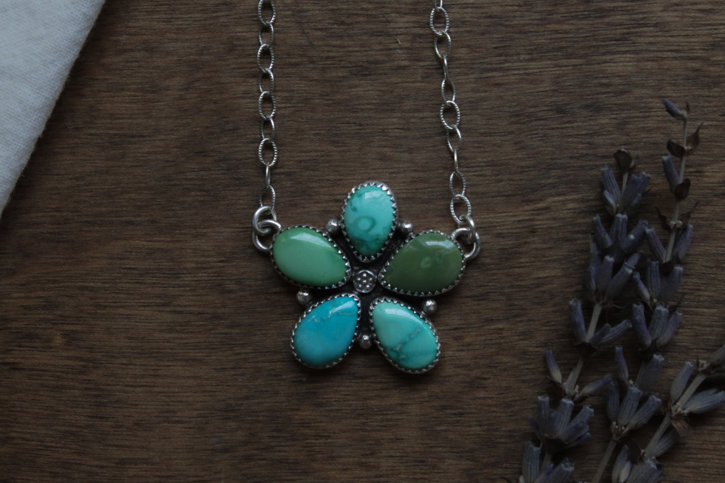 Wildflower Turquoise Necklace with genuine Emerald Valley Turquoise gemstones, handcrafted in responsibly recycled sterling silver. Vibrant teardrop turquoise stones form a unique wildflower cluster pendant on an 18-inch oxidized sterling silver chain, polished to a satin finish. Sustainable, one-of-a-kind artisan statement necklace.