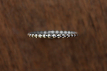 Handmade sterling silver stacker ring with a beaded pattern on a wooden surface