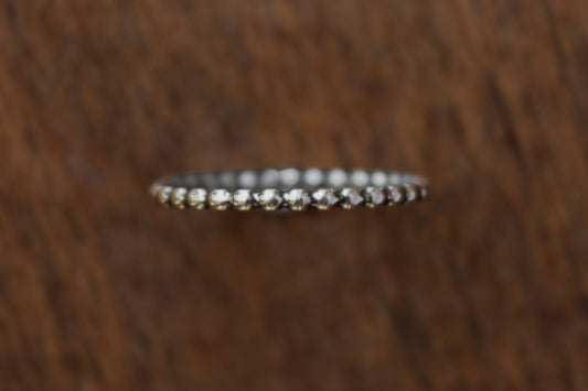 Handmade sterling silver stacker ring with a beaded pattern on a wooden surface
