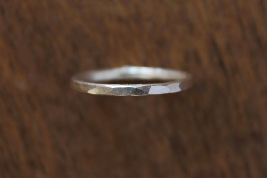 Handmade sterling silver ring with a sparkling hammered texture on a wooden surface